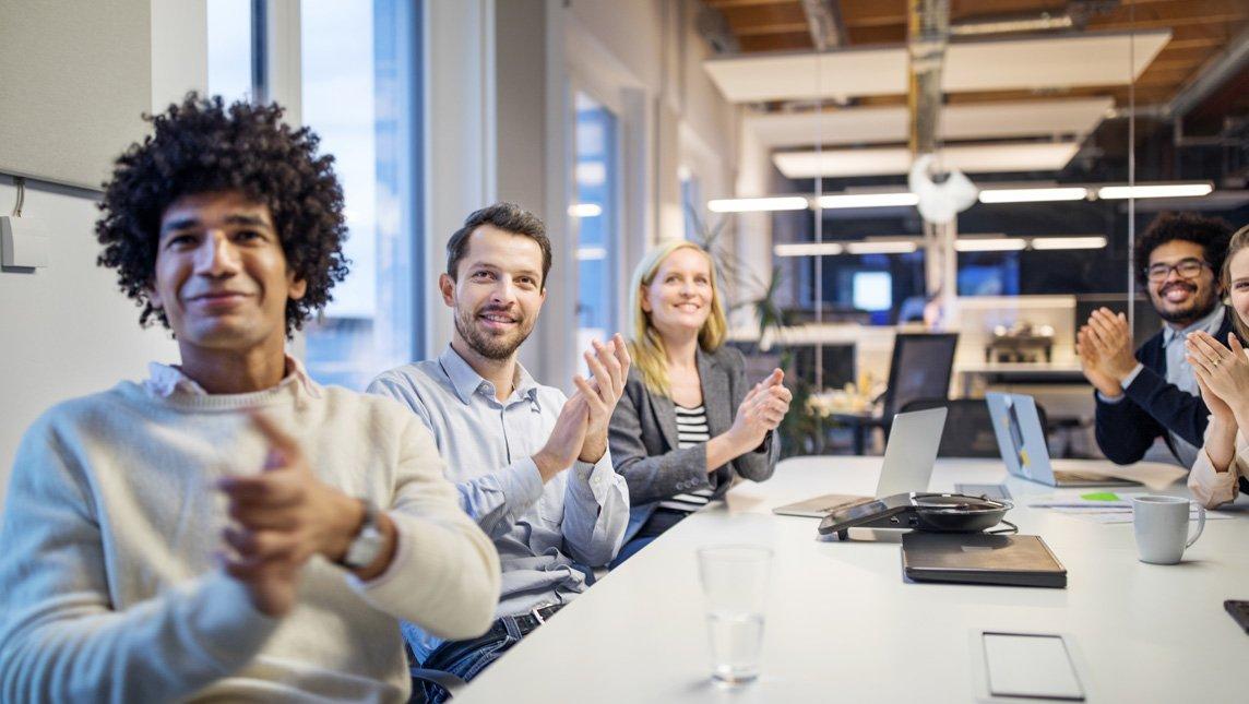 Business team applauding while in meeting at modern office