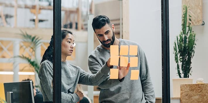 Staff collaborate on a wall using sticky notes.