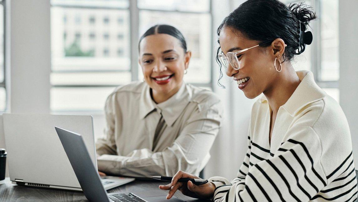 A woman uses her laptop outside a building.