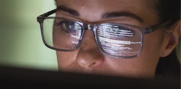 A programmer looks at a computer screen with code projects on her glasses.