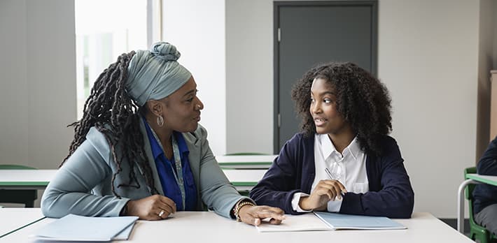 A student and their teacher in a classroom.