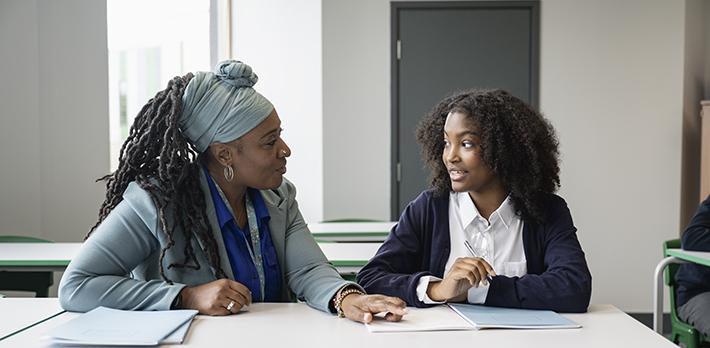 A student and their teacher in a classroom.
