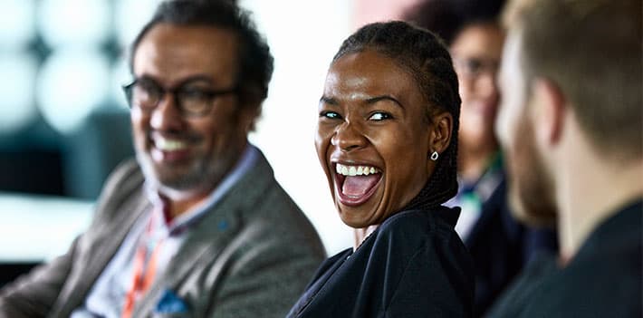 Conference attendees smile as they talk together.