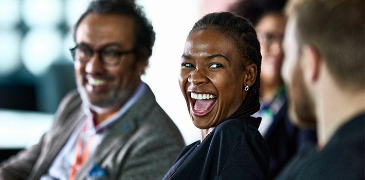 Conference attendees smile as they talk together.