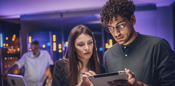 Two college staff looking at a laptop.