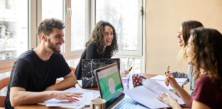 Students sitting at a table with laptops