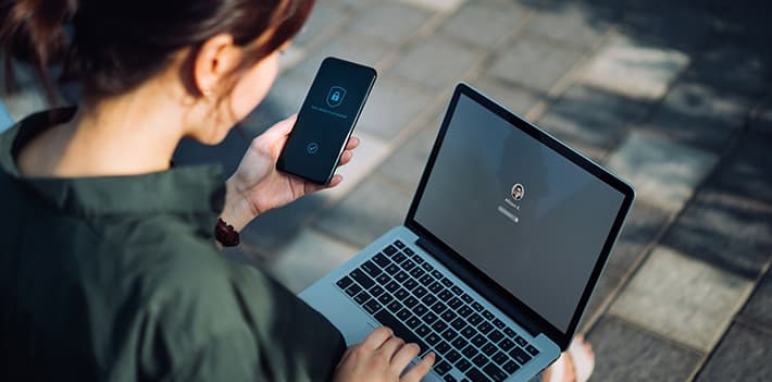 Woman looking at a laptop and a mobile phone screen