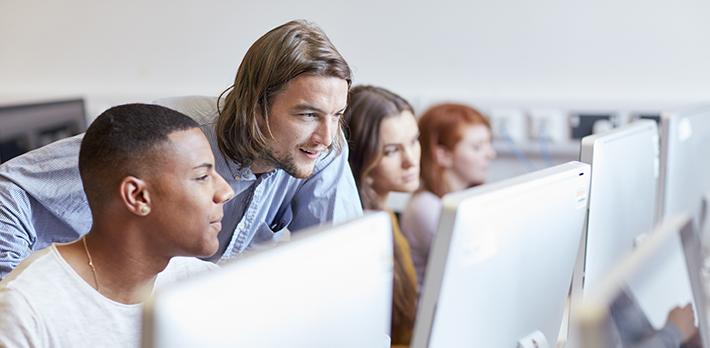 A teacher helps a student in a computer room.