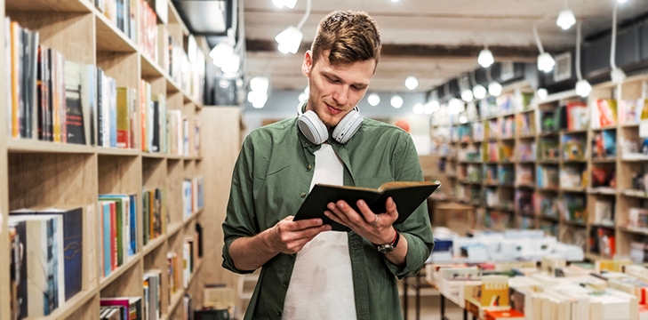 Male student in a library reading a book.
