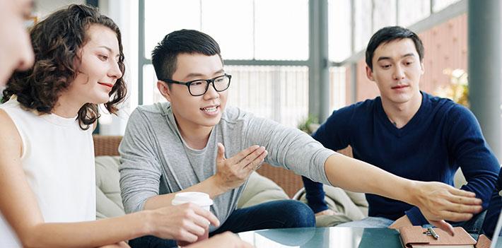 Colleagues discuss a computer screen in the workplace.